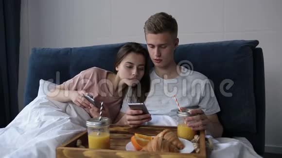 情侣共用手机在床上观看媒体内容视频的预览图