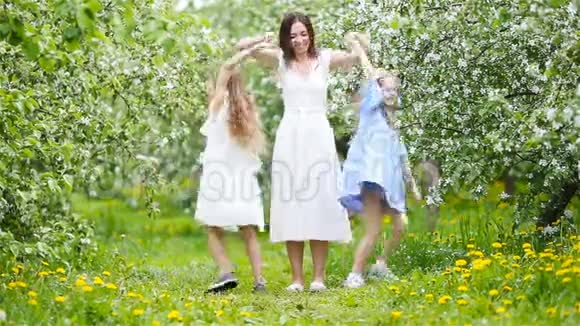 美丽的春日可爱的小女孩和年轻的母亲在盛开的花园里一起玩视频的预览图