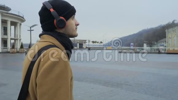 年轻人带着耳机听音乐走在城里视频的预览图