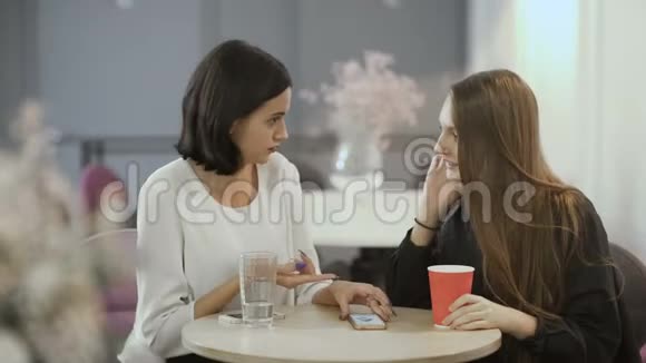 两个漂亮的女孩在桌旁说话视频的预览图