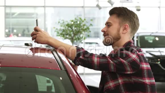 使用智能手机显示汽车钥匙和相机在经销商摆姿势的快乐男人视频的预览图