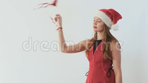 穿着圣诞老人帽子的可爱女孩挥舞着一根装饰棒和丝带视频的预览图
