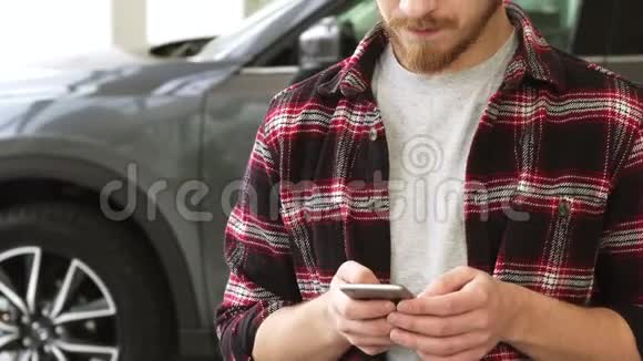 在经销商店买新车时使用智能手机的胡子帅哥视频的预览图