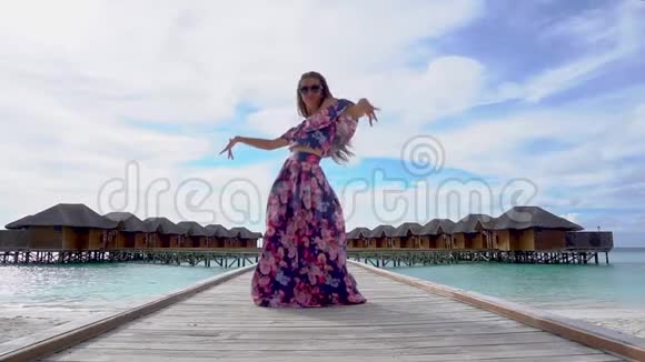 马尔代夫有透明的海水在沙滩上的桥上跳舞的妇女视频的预览图