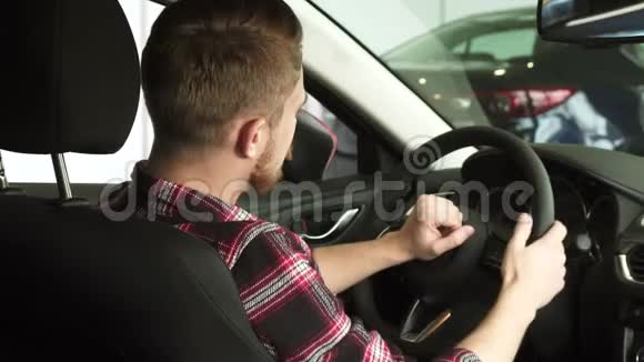 坐在一辆新车里一个漂亮的留着胡子的男人肩膀上对着镜头微笑视频的预览图