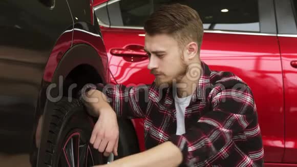 在经销商处检查新车车轮和轮胎的年轻人视频的预览图