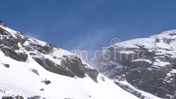 刮起一股强烈的风在山上的峰峦上吹起雪花视频的预览图