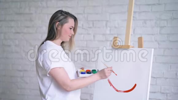 一个女孩的艺术家在白色的帆布上画了一个微笑视频的预览图