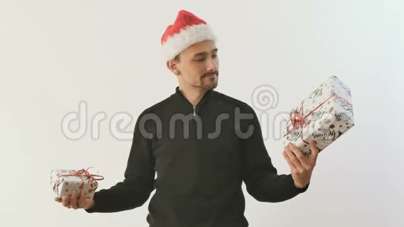 戴着圣诞老人帽子的人把两件白色背景的礼物拿在手里视频的预览图