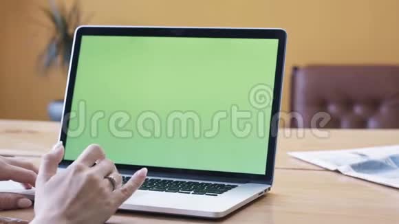 穿着粉红色衬衫的年轻女子坐在大木桌旁用彩色钥匙绿色屏幕在笔记本电脑上打字股票视频的预览图
