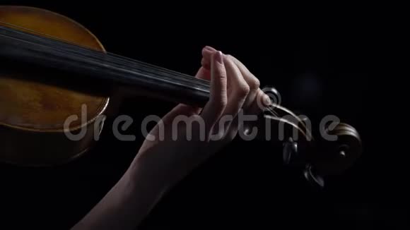 女孩用手指弹奏小提琴的琴弦快关门黑色背景视频的预览图