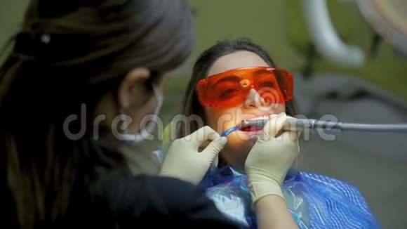 女医生口腔医生在医疗牙科诊所为年轻女性患者治疗和美白牙齿视频的预览图