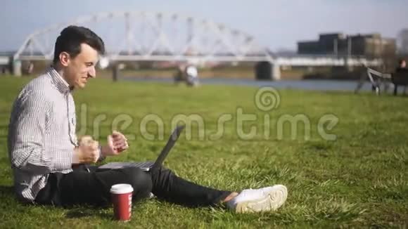 男孩检查笔记本电脑并收到好消息一个人坐在公园里一个人刚刚赢得了一个大奖终于发生了视频的预览图