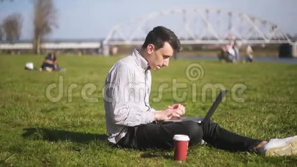 男孩检查笔记本电脑并收到好消息一个人坐在公园里一个人刚刚赢得了一个大奖终于发生了视频的预览图
