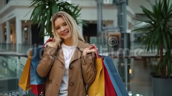 笑的女孩站在商场里肩上扛着购物袋视频的预览图