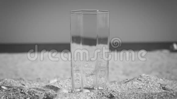 黑白玻璃填充饮用水海滩上以大海为背景特写视频的预览图