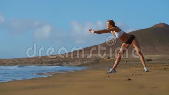 女人伸展腿和腿筋做站立前弯曲瑜伽伸展姿势在海滩上健身妇女放松身心视频的预览图