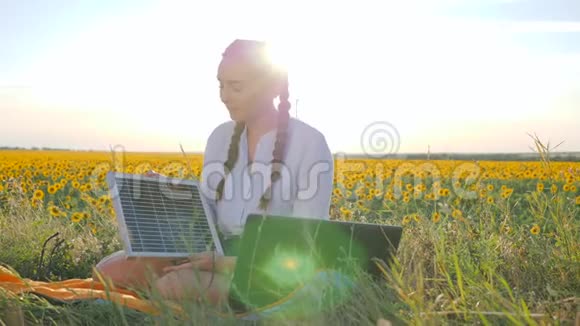清洁能源年轻女性在户外使用太阳能电池板在笔记本电脑上交谈女性在背光下使用笔记本充电器视频的预览图