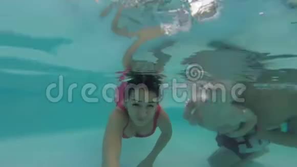 一个带着孩子的小家庭在一个开放的游泳池里在水下潜水赛尔夫视频的预览图