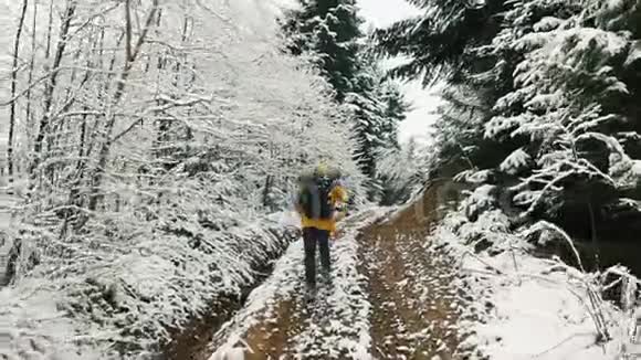 穿着黄色夹克的人沿着积雪覆盖的山间小径跑了上来冬季视频的预览图