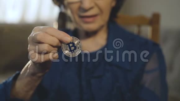 快乐的老妇人展示了一枚银比特币用于相机和微笑视频的预览图