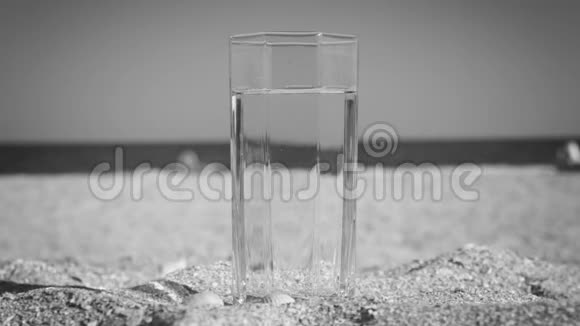 黑白特写玻璃与饮用水站在沙滩上的沙滩那个女孩拿着玻璃杯擦了擦视频的预览图