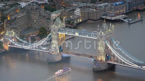 从伦敦塔桥下泰晤士河上俯瞰日落黄昏城市灯光的空中全景视频的预览图