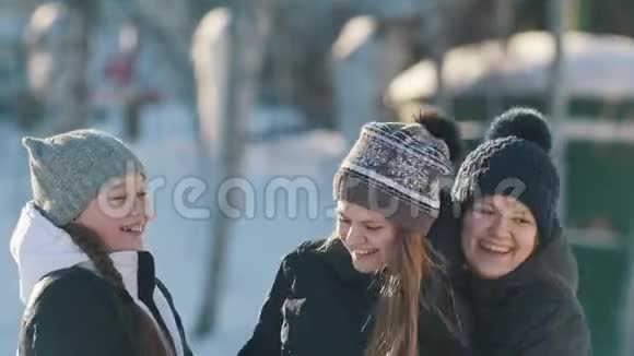 三个十几岁的女孩在冬天在外面摆姿势拥抱和微笑的肖像视频的预览图