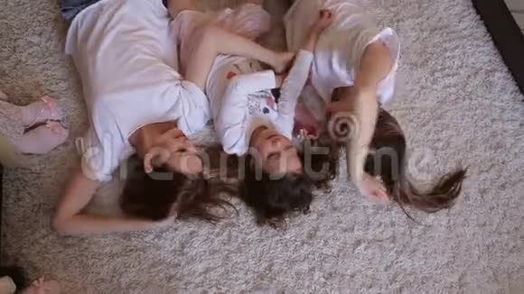 三个姐妹躺在地板上铺着蓬松的地毯视频的预览图