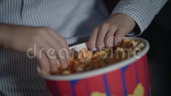 儿童手拿爆米花从纸盒在电影院孩子们拿着焦糖爆米花视频的预览图