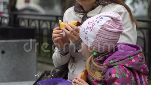 年轻的女人和她的小女儿在公园凉爽的一天吃三明治视频的预览图