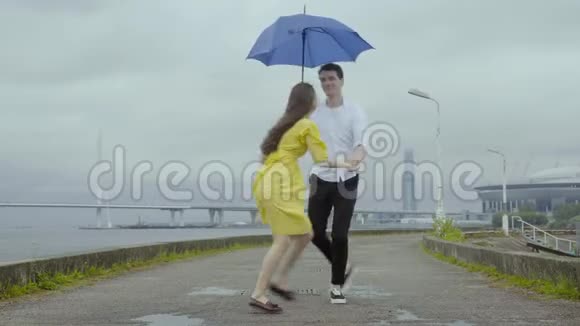 在这座城市的堤岸上浪漫的情侣在雨中跳舞视频的预览图