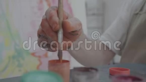 艺术家用画笔从瓶子里取出橙色颜料视频的预览图