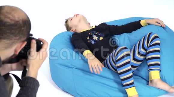 摄影师在豆袋里给穿睡衣的可爱小男孩拍照视频的预览图