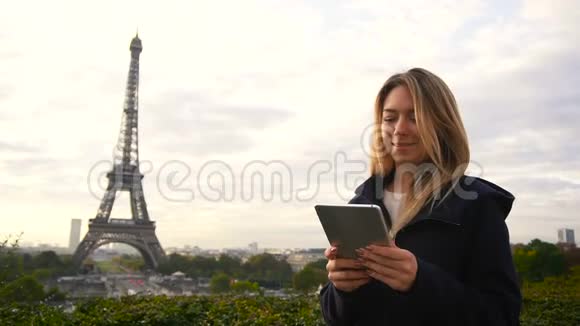 性格开朗的女人用平板电脑做视频通话以埃菲尔铁塔为背景动作缓慢视频的预览图