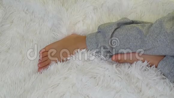 孩子的腿慢慢地躺在白色的地毯上视频的预览图