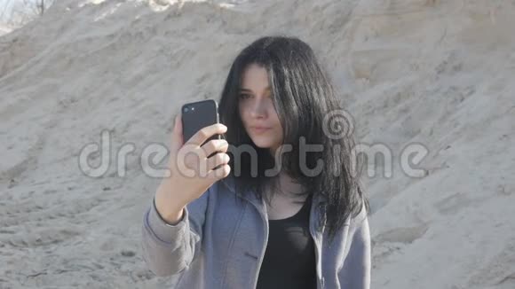 可爱的黑发女人用智能手机自拍的肖像风很容易吹动她的头发视频的预览图