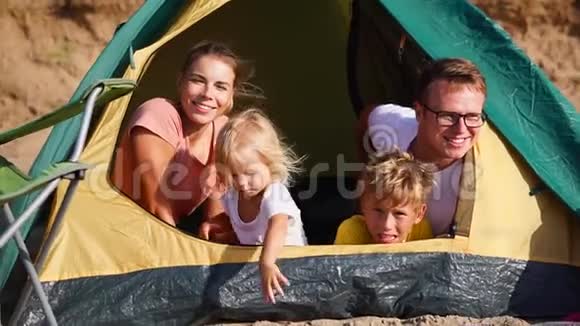 一家人在海滩上度过快乐的日子在帐篷里配偶和孩子微笑着视频的预览图