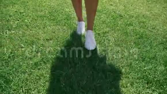 穿着白色鞋子在草坪上行走特写只有腿和影子视频的预览图