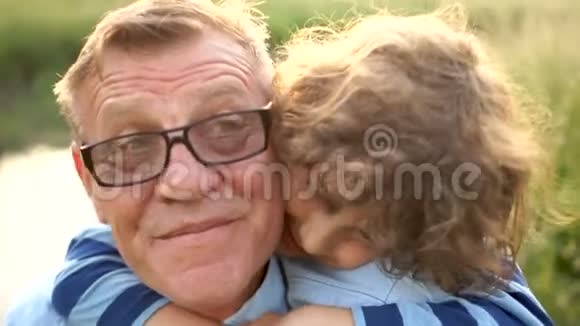 可爱的卷曲孙子拥抱他的祖父一个戴眼镜的养老金领取者和他的孙子在河边上学视频的预览图