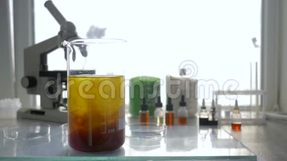 实验室在无聚焦背景下将试剂与棒状混合物放在桌子上的大玻璃中视频的预览图
