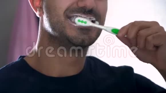 男人在浴室的镜子前刷牙一个年轻人在镜子里的倒影一种平静和疲惫视频的预览图