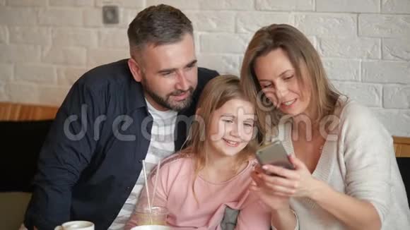 幸福家庭在SmarthphoneIndoors上做自拍的肖像他们在咖啡厅度过这美好的一天视频的预览图