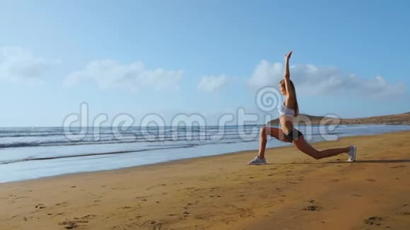 做腿部伸展运动的女人健身女孩伸展腿在海滩训练慢动作稳定视频的预览图