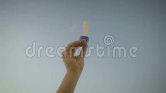 在阳光明媚的一天一只手在风中吹着肥皂泡在天空中特写视频的预览图