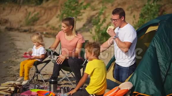 一个年轻的家庭在沙滩上安排了一天的午餐帐篷在海边视频的预览图