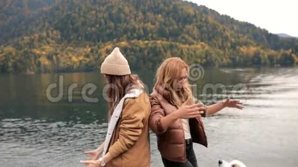 两个年轻时尚的白人女性在山上的湖上玩她的边境牧羊犬旅费视频的预览图
