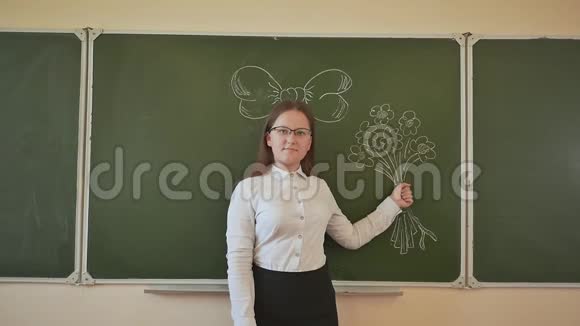 女学生高年级学生拿着虚拟的花头上戴着蝴蝶结花和蝴蝶结画在学校的黑板上视频的预览图