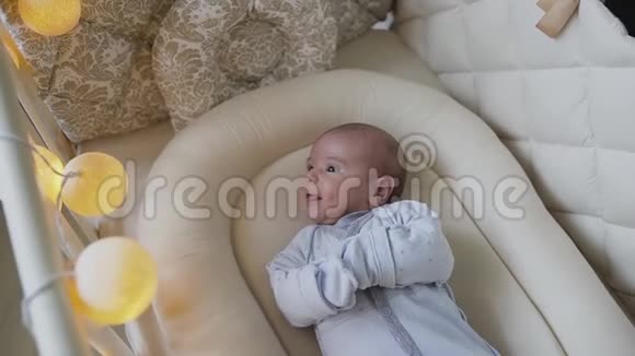 一个穿着蓝色婴儿滑块的新生婴儿躺在卧室家中的婴儿床上小男孩想在床上睡着视频的预览图