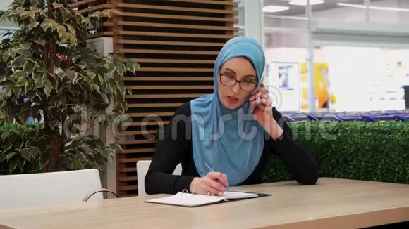 穆斯林女孩打电话写在笔记本上视频的预览图